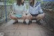 Two young women in school uniforms sitting on a brick walkway.