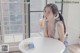 A woman sitting at a table eating a banana.