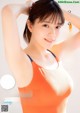 A woman in an orange tank top posing for a magazine cover.