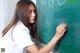 A young woman writing on a blackboard with chalk.