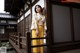 A woman in a yellow kimono standing on a wooden bridge.