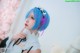 A woman with blue hair wearing a white dress and a pink bow.