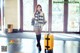 A woman with a yellow suitcase standing in front of a door.