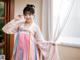 A woman in a pink and blue hanbok posing for a picture.