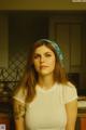 A woman with a bandana on her head standing in a kitchen.