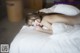 A naked woman laying on a bed with white sheets.