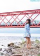 A woman standing on a rocky beach next to a body of water.