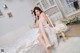 A woman in a white dress sitting on a bed.