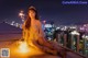 A woman sitting on top of a building holding a sparkler.